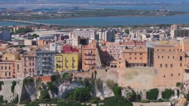 Cagliaris Castello ilçesinde ortaçağ mimarisi, Bastione di Saint Remy ve Akdeniz ve uzak dağlarla çevrili bir şehir manzarası bulunur..
