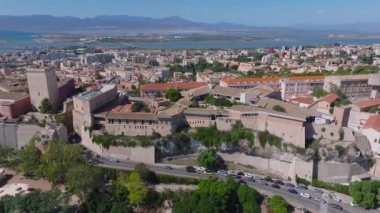 Cagliaris Castello ilçesinde ortaçağ mimarisi, Bastione di Saint Remy ve Akdeniz ve uzak dağlarla çevrili bir şehir manzarası bulunur..