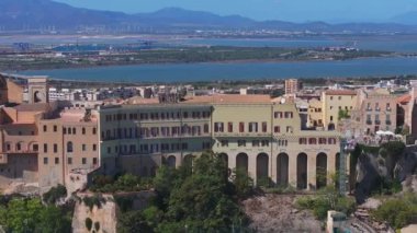 Cagliaris Castello ilçesinde ortaçağ mimarisi, Bastione di Saint Remy ve Akdeniz ve uzak dağlarla çevrili bir şehir manzarası bulunur..
