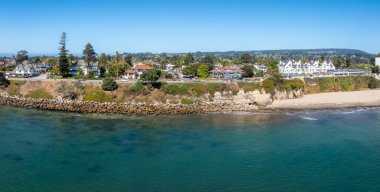 Santa Cruz, California 'nın hava manzarasında kayalık bir kıyı şeridi, kumlu plaj, uçurumlar ve büyüleyici evler var. Yeşillik yemyeşil ve tepeler arka planda.