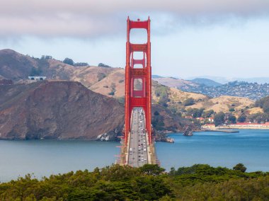 Golden Gate Köprüsü, Marin Burunları ve parçalı bulutlu gökyüzü ile çelişen Uluslararası Portakal rengi ile San Francisco Körfezi boyunca uzanır..