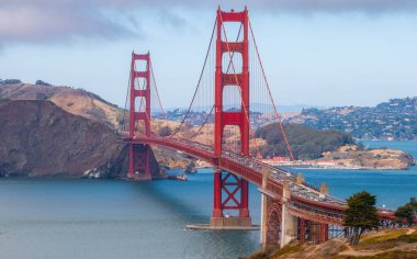 Golden Gate Köprüleri kırmızı turuncu kuleler ve kablolar mavi San Francisco Körfezi boyunca uzanır, Marin Burnu tepeleri ve şehir manzarası uzaktadır..