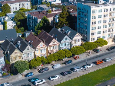 San Francisco 'daki Viktorya Dönemi Boyalı Kadınlar modern binalar ve yeşilliklerle tezat oluşturuyor. Park halindeki arabalar caddelerde, kentsel unsurları vurguluyor..