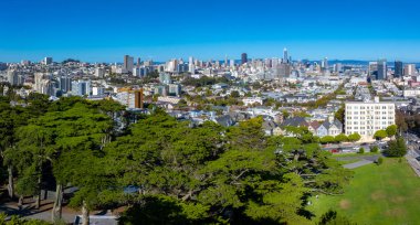 San Fransisko şehir merkezindeki Satış Gücü Kulesi 'nin panoramik görüntüsü. Bereketli yeşillik ve açık mavi gökyüzünün altında park alanı.