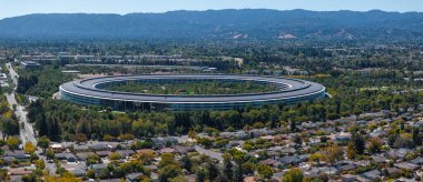 Görüntü Cupertino, Kaliforniya 'daki dairesel Apple Park kampüsünü, yeşillik ve yerleşim alanlarıyla çevrelenmiş, arka planda Santa Cruz Dağları' nı yakalıyor..