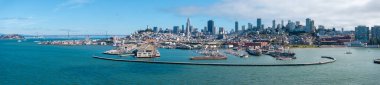 San Francisco 'nun panoramik hava manzarasında Transamerica Piramidi, Bay Köprüsü, hareketli kıyı şeridi ve Alcatraz Adası berrak mavi gökyüzü altında..