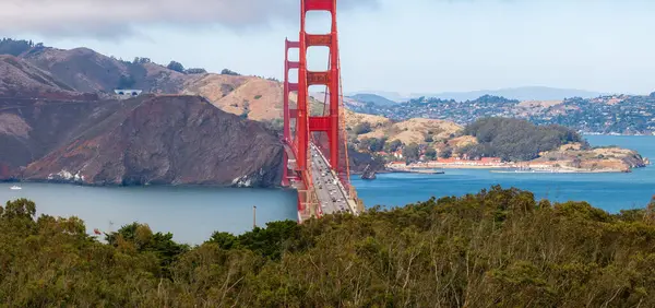 Golden Gate Köprüsü 'nün ikonik kırmızı turuncu kuleleri San Francisco Körfezi' nin mavi suları boyunca uzanır ve arka planda Marin County tepeleri bulunur..