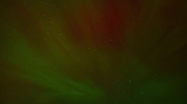 Parlak yeşil aurora borealis, durgun su üzerinde gece gökyüzünü aydınlatır. Parlak bir meteor ya da uydu olay yerinde hızla ilerler..