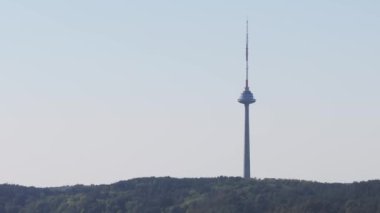 Vilnius TV Kulesi yemyeşil bir zemin üzerinde dimdik duruyor, kendine özgü yapısını ve çevresindeki orman alanını vurguluyor..