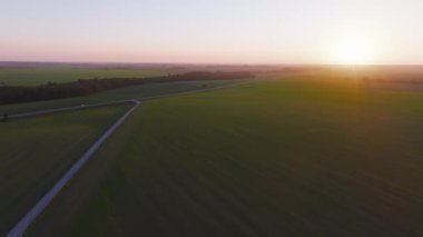 Hava görüntüsü, günbatımını Litvanya çayırları, Haçlar Tepesi ve güneş panelleri üzerinde, doğal güzellik, kültür mirası ve modern enerjiyi harmanlayarak yakalıyor..