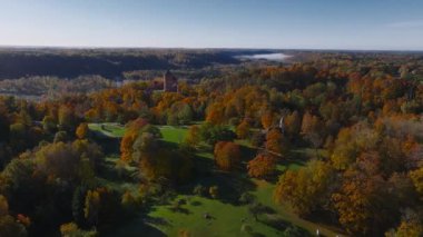 Letonya, Sigulda 'daki Turaida Kalesi' ni çevreleyen canlı sonbahar renklerini ortaçağ mimarisini vurgulayan havadan bir perspektifle keşfedin..