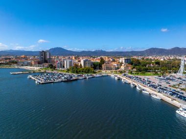 Olbia, Sardunya 'nın havadan görünüşü, tekneli bir marina, bir park alanı, tepelere ve dağlara karşı modern ve geleneksel binaların silueti..