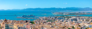 Tarihsel ve modern mimari, kenetlenmiş bir yolcu gemisi ve engebeli dağlarla Akdeniz 'in yer aldığı Cagliari, Sardunya' nın hava manzarası..