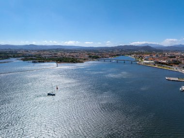 Olbia, Sardunya 'nın hava perspektifi, Olbia Körfezi' ni içerir, bir köprü, şehir yapıları, yeşillik ve yalnız bir yelkenli..