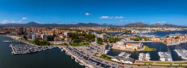 Olbia, Sardinya 'nın havadan görünüşü, yatları, modern ve geleneksel mimarisi olan bir marinaya ve berrak bir gökyüzünün altındaki tepelerin arka planına sahip..