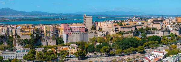 Cagliaris Castello bölgesinde antik kaleler ve renkli binalar bulunmaktadır. Arka planda Torre di San Pancrazio ve Cagliari Körfezi görünüyor..