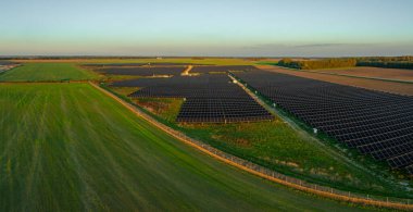 Litvanya 'da geniş bir güneş paneli kurulumunun hava perspektifi, açık bir gökyüzü altında sıralanmış yeşil paneller, yenilenebilir enerji sergiliyor.