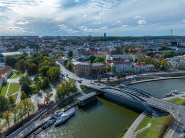 Vilnius, Litvanya 'nın hava perspektifi, Neris Nehri, modern bir köprü, tarihi binalar, ve parçalı bulutlu gökyüzü altındaki Vilnius TV Kulesi.