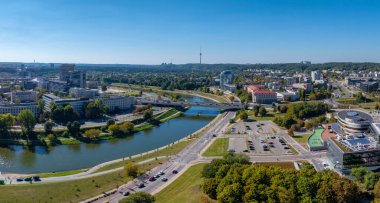 Vilnius, Litvanya 'nın hava manzarası, Neris Nehri, yemyeşil alanlar, modern binalar, ve açık mavi gökyüzü altındaki uzak Vilnius TV Kulesi..