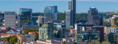 Litvanya, Vilnius 'un gökdelenler ve tarihi binaların karışımından oluşan hava manzarası. Bereketli yeşil bir orman şehir manzarasına zıt düşüyor..