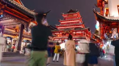 Şanghay 'ın eski şehrinin gece vakitleri, gösterişli çatıları ve coşkulu kalabalıklar arasında parlayan kırmızı ışıkları olan geleneksel Çin mimarisini sergiliyor..