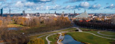 Riga, Letonya 'nın hava manzarası, viraj yolları ve göletle Victory Park' ı aydınlatıyor. Ulusal Kütüphane, dönme dolap ve Vansu Köprüsü görülebilir durumda..