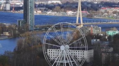 Riga 'nın hava manzarasında Zafer Parkı, bir köprüsü olan Daugava Nehri ve kentsel ve doğal manzaraların ortasındaki modern bir bina görülüyor..