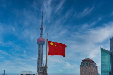 Doğu İnci Kulesi Şangay 'daki modern gökdelenlerin ortasında duruyor. Çin ulusal bayrağı açık mavi gökyüzüne karşı dalgalanır..