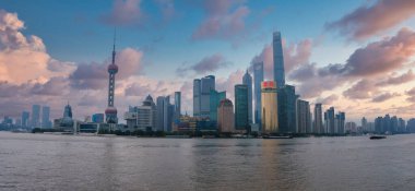 Şangay 'ın ufuk çizgisi Doğu İnci Kulesi ve Şangay Kulesi' ne sahiptir, modern gökdelenler renkli bulutların altında Huangpu Nehri 'ne yansımaktadır..