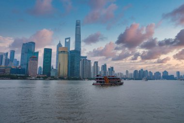 Şangay 'ın Pudong bölgesinin ufuk çizgisi, Şangay Kulesi, Dünya Finans Merkezi ve Jin Mao Kulesi. Geleneksel bir tekne Huangpu Nehri 'nde yol alır..