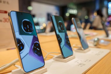 Modern akıllı telefonlardan oluşan bir koleksiyon Şangay 'daki bir perakende mağazasında ahşap bir masaya yerleştirildi. Her telefon bir kamera modülü tasarımı ile canlı bir ekran görüntüler.