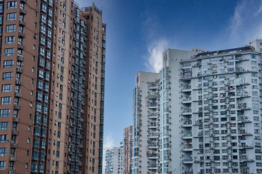 Çin 'in Şangay kentindeki modern yüksek binalar kümesi, kahverengi ve açık gri cepheler, sayısız balkon ve açık mavi bir gökyüzü içeriyor..