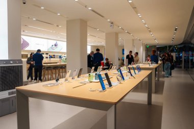 A spacious electronics store in Shanghai features sleek design, wooden tables with smartphones, bright lighting, and staff assisting customers. clipart