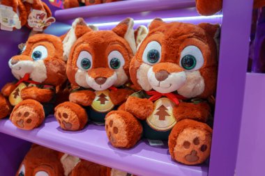 Pofuduk tilki oyuncaklarının büyük gözleri ve çalı kuyruklu koleksiyonu, her biri bir Noel ağacı amblemi içeriyor, bir perakende mor rafta canlı bir şekilde sergileniyor..