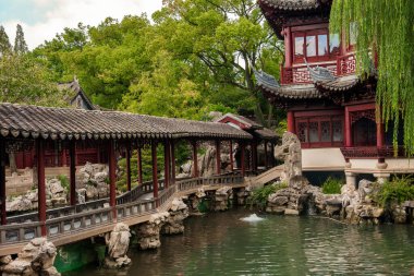 Söğüt ağaçları, yemyeşil yeşillikler ve kaya oluşumlarıyla çevrili, Şangay bahçesindeki sakin bir göletin üzerinde eğimli çatıları olan klasik bir pavyon duruyor..
