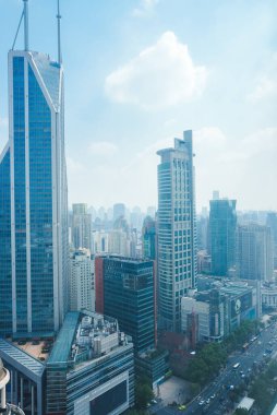 Shanghai 'nin gökdelenlerin ortasındaki Jin Mao Kulesi' nin göz alıcı manzarası, açık mavi gökyüzünün altında, aşağısı hareketli caddelerle dolu.