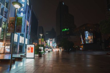 A nighttime scene in Shanghai shows a well lit pedestrian street with modern buildings, bright signs in Chinese, and tall skyscrapers in the background. clipart