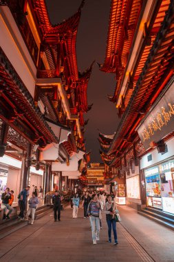 A bustling pedestrian area in Shanghai showcases traditional Chinese architecture with ornate eaves, surrounded by shops and signs in Chinese characters. clipart