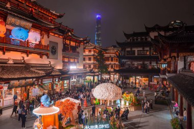 Şangay 'daki Yuyuan Old Street' in ışıl ışıl gece manzarası, aydınlık çatıları ve uzaktaki modern Şangay Kulesi ile geleneksel mimariyi gözler önüne seriyor..