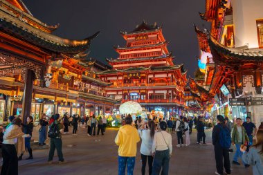 Şangay 'daki Yuyuan Eski Caddesi geceleri aydınlanıyor, geleneksel mimariyi karmaşık ahşap oymalarla sergiliyor. Kalabalık canlı meydanda toplanıyor..