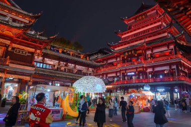 Gece vakti Şangay 'da geleneksel Çin mimarisi, hareketli kalabalık ve parlayan mantar vitrinleri de dahil olmak üzere modern mağazalar yer alıyor..