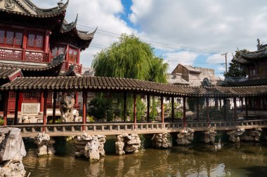 Şangay 'daki Yuyuan Garden' da ahşap oymalarla kaplı bir yürüyüş yolu, kaya oluşumları, yemyeşil yemyeşil ve geleneksel binalarla dolu bir gölet bulunuyor..
