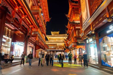 Shanghais 'in eski kasabasının canlı gece manzarası, geleneksel Çin mimarisinin süslenmiş ahşap cepheleri ve parlak kırmızı fenerleriyle.
