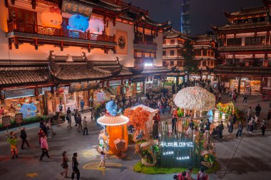 Şangay 'daki Yuyuan Old Street' in canlı gece manzarası geleneksel mimari, renkli dekorasyonlar ve arka planda modern bir gökdelen..
