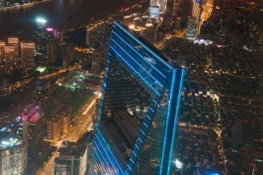 Aerial view of Shanghai at night with the Shanghai World Financial Center, modern skyscrapers, and the Huangpu River illuminated by city lights. clipart