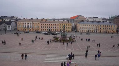 Helsinki, Finlandiya 'daki Senato Meydanı manzarasında Alexander II heykeli, neoklasik mimari ve bulutlu gökyüzü altındaki Helsinki Katedrali yer almaktadır..