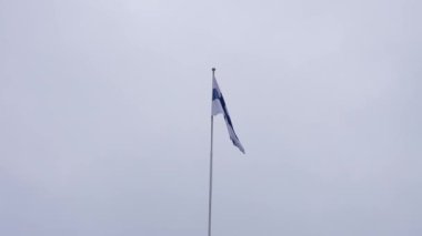 Finlandiya bayrağı bulutlu gökyüzüne hafifçe sallanarak Helsinki 'nin serin ve bulutlu ikliminde ulusal bir gurur hissi uyandırır..