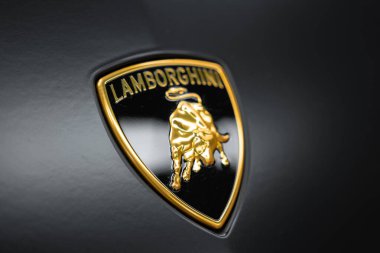 Görüntü, Lamborghini ambleminin siyah bir kalkanda altın bir boğa ile detaylı bir görüntüsünü gösteriyor. Urus Performante 'nin parlak yüzeyine ayarlanmış..