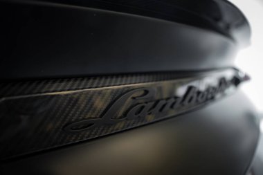 Görüntü bir Lamborghini 'nin arka kısmını yakalıyor, karbon fiber detaylara ve ambleme odaklanıyor. İçerideki ışıklandırma, lüks işçiliğin altını çiziyor.