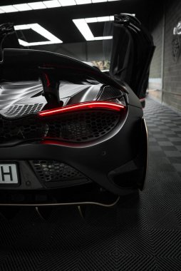 McLaren 720 kapalı alanda sergileniyor, aerodinamik tasarımı ve ayırt edici stop lambaları sergileniyor. Makas kapılarını aç, lüks görünümünü arttır..